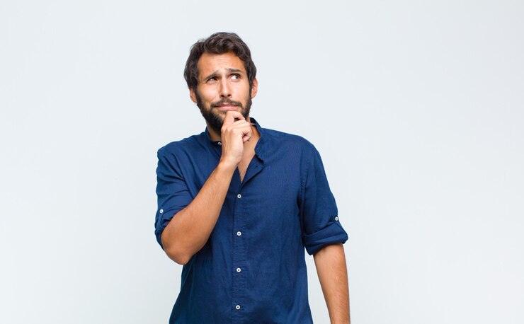 Foto joven guapo pensando, sintiéndose dudoso y confundido