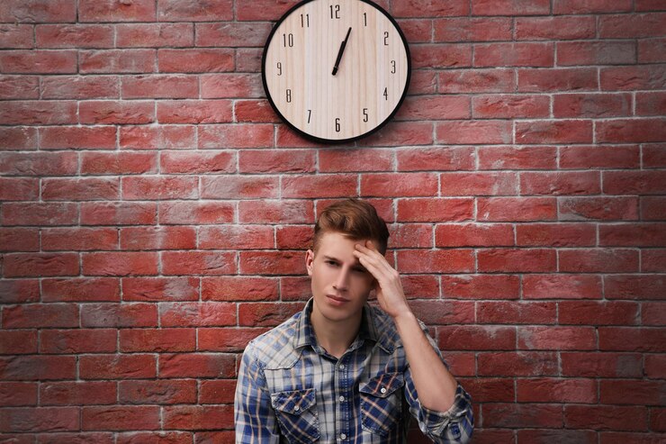 Foto joven guapo y reloj en pared de ladrillo
