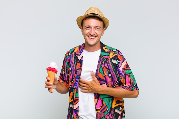 Joven guapo riendo a carcajadas de una broma hilarante, sintiéndose feliz y alegre, divirtiéndose