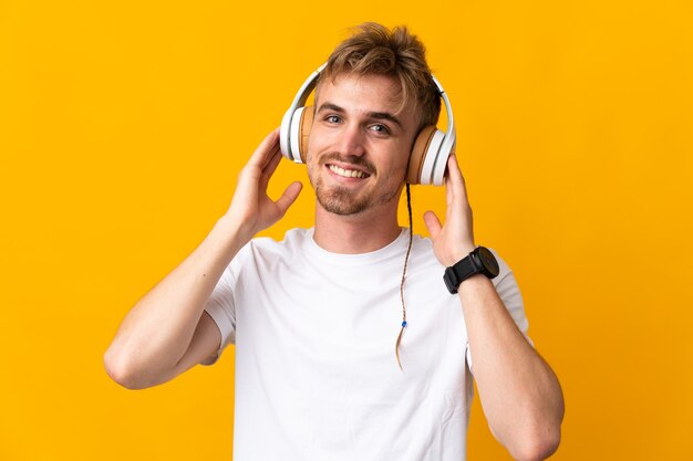 Joven guapo rubio aislado escuchando música