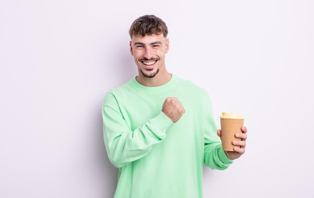 Joven guapo sintiéndose feliz y enfrentando un desafío o celebrando. concepto de café para llevar