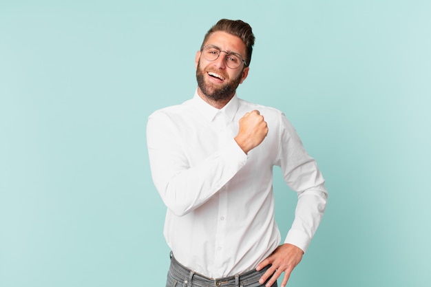 Joven guapo sintiéndose feliz y enfrentando un desafío o celebrando