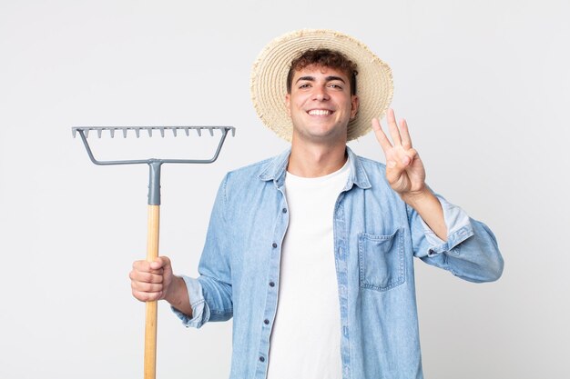 joven guapo sonriendo y luciendo amigable, mostrando el número tres. concepto de granjero