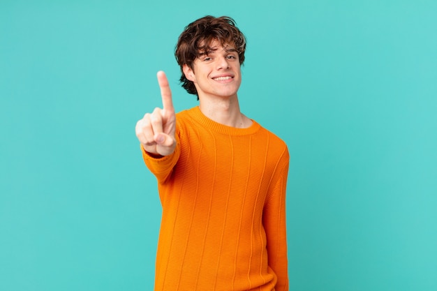 joven guapo sonriendo con orgullo y confianza haciendo el número uno