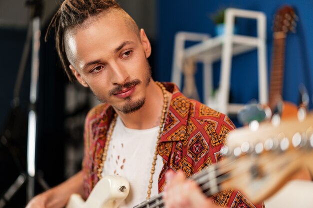 Joven guitarrista sentado y actuando en un sofá en la sala de estar