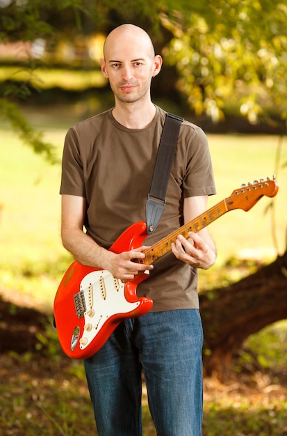 Joven guitarrista, tocando la guitarra en un hermoso entorno natural