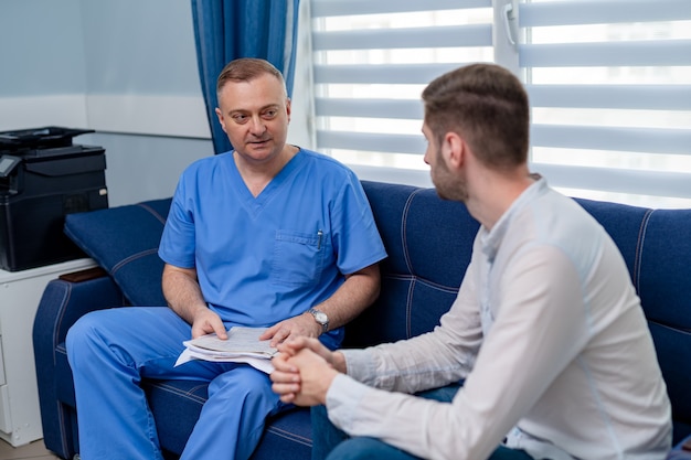 Joven hablando con un médico que lee los resultados de un examen médico. Visita al hospital.