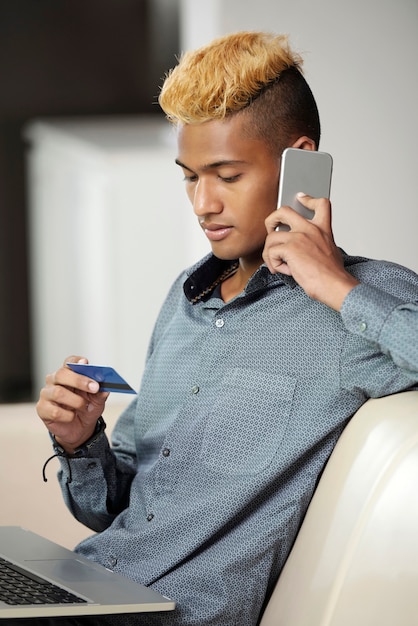 Joven hablando por teléfono con el gerente del banco cuando tiene problemas con la nueva tarjeta de crédito