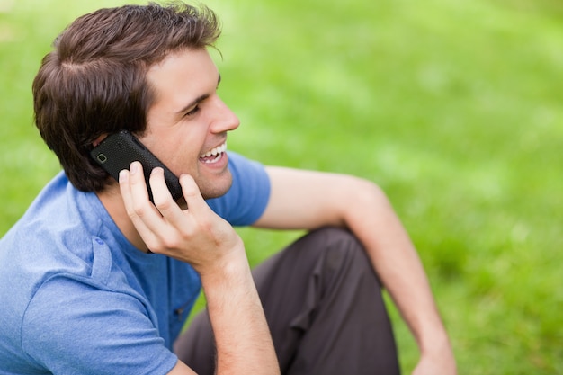 Joven hablando por teléfono mientras está sentado en la hierba