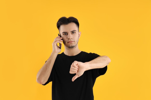 Joven hablar por teléfono sobre fondo amarillo