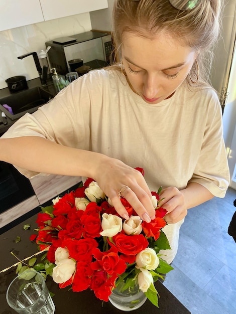 Una joven hace un ramo de rosas rojas.