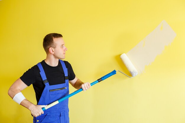 Un joven hace reparaciones en el apartamento, ok vuelve a pintar las paredes en un color diferente