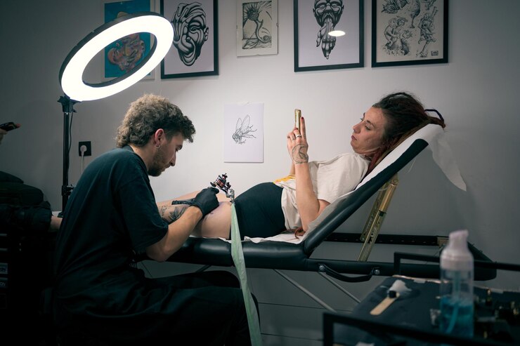 Una joven se hace un tatuaje en la pierna de un artista profesional en un estudio