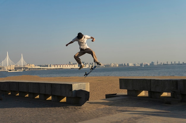Un joven hace un truco en una patineta de madera en el aire bajo el sol poniente en la calle