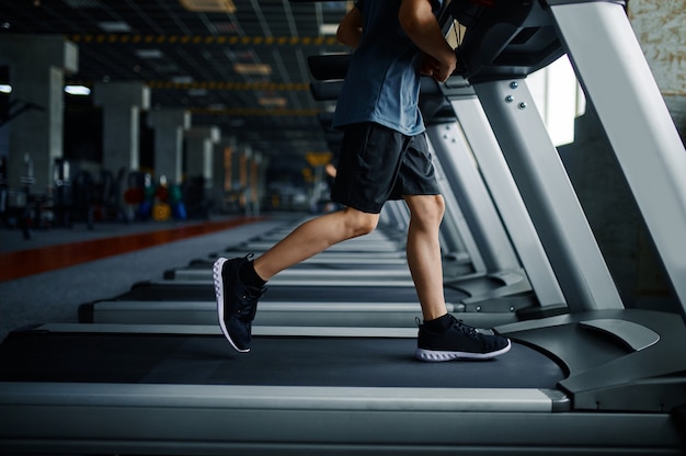 Joven haciendo ejercicio en la caminadora en el gimnasio, máquina para correr. Niño en entrenamiento en club deportivo, cuidado de la salud y estilo de vida saludable, niño en entrenamiento