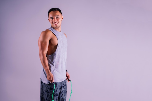 Foto joven haciendo ejercicio con una cuerda para saltar y mirando a la cámara aislada sobre un fondo gris