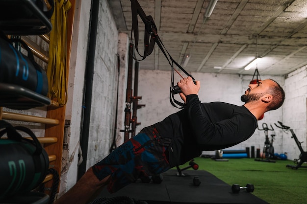 Joven haciendo ejercicio multifuncional en el gimnasio