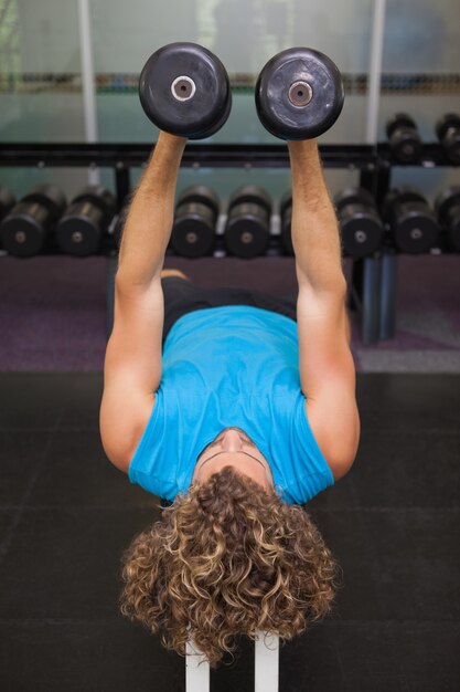 Foto joven haciendo ejercicio con pesas en el gimnasio