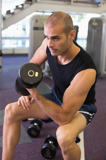 Joven haciendo ejercicio con pesas en el gimnasio