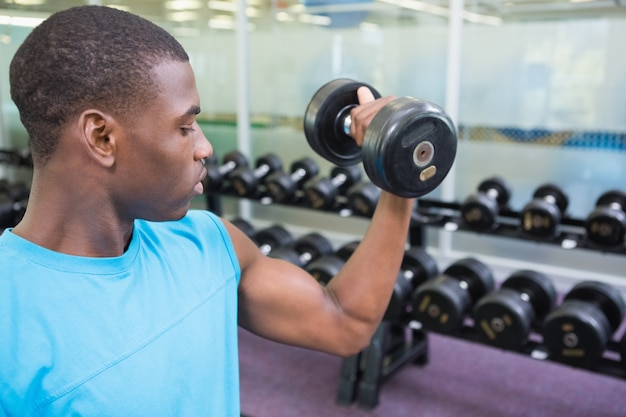 Joven haciendo ejercicio con pesas en el gimnasio