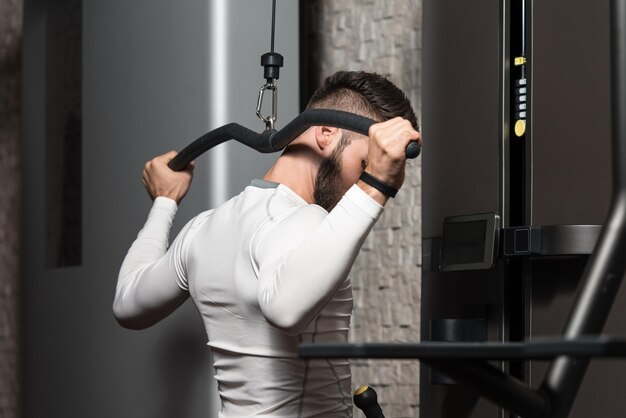 Joven haciendo ejercicio de peso pesado para la espalda en el gimnasio