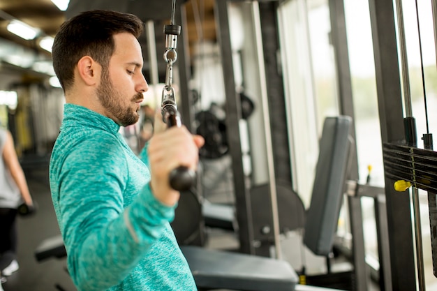 Joven haciendo ejercicio para tríceps en el gimnasio en mashine