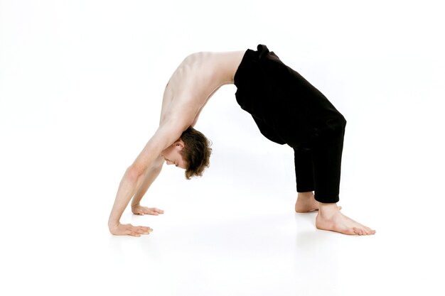 Joven haciendo ejercicios de yoga foto de estudio sobre fondo blanco.