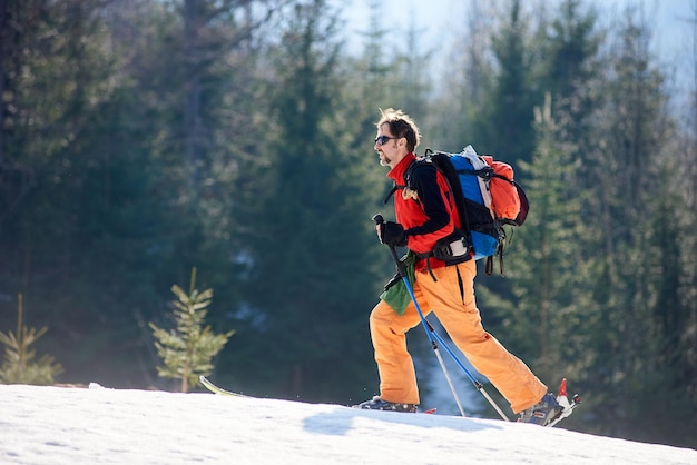 Joven haciendo esquí de travesía en las montañas de invierno en un día soleado