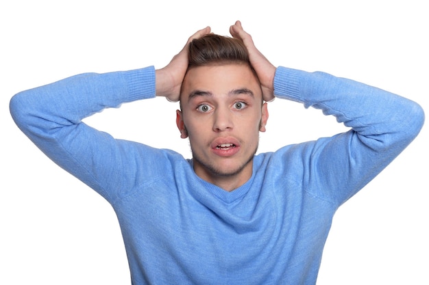 Joven haciendo expresión facial contra el fondo blanco.