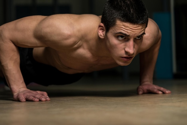 Joven haciendo flexiones en el gimnasio