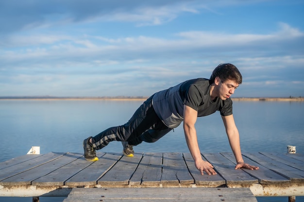 Joven haciendo flexiones en un lago