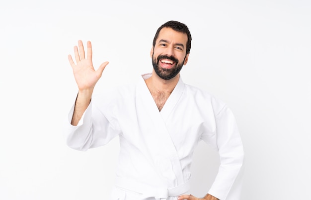 Joven haciendo karate saludando con la mano con expresión feliz