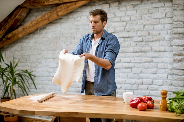 Joven haciendo masa en la cocina rústica