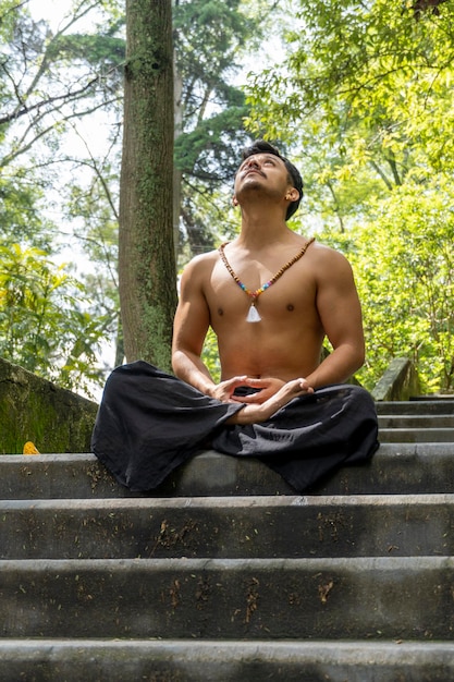 Joven haciendo meditación en una escalera en un bosque méxico