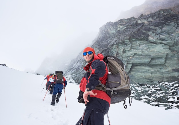 Joven haciendo senderismo en las montañas de invierno con amigos