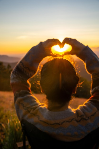 Foto una joven haciendo un símbolo de corazón con sus manos al atardecer