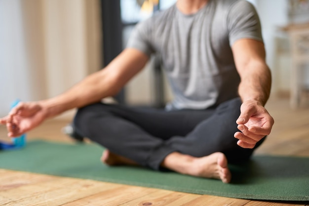 Joven haciendo el símbolo de gyan mudra y meditando en casa