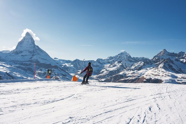 Joven haciendo snowboard en la estación de esquí de zermatt justo al lado del famoso pico Matterhorn