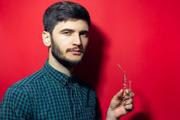 joven haciendo un tratamiento de respiración con inhalador de mahold y aceite esencial. Aislado en la pared roja.