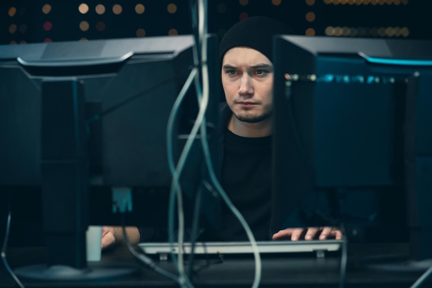 Joven hacker masculino profesional que usa el teclado para escribir datos incorrectos en el sistema informático en línea