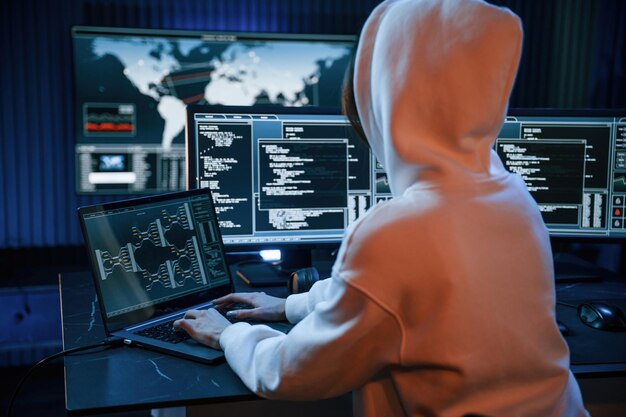 Una joven hacker profesional está en el interior de una computadora con mucha información en las pantallas.