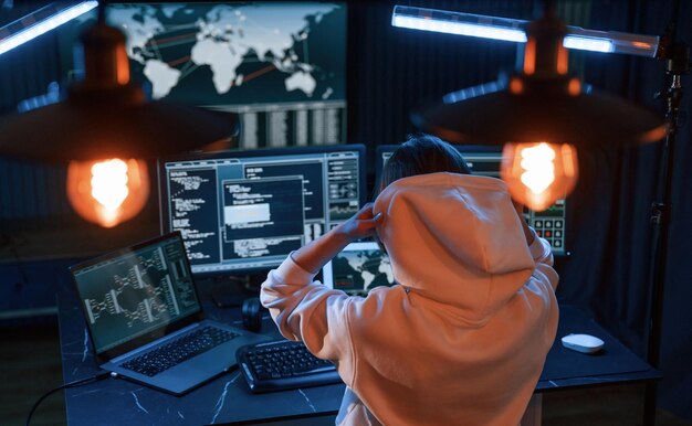 Una joven hacker profesional está en el interior de una computadora con mucha información en las pantallas.