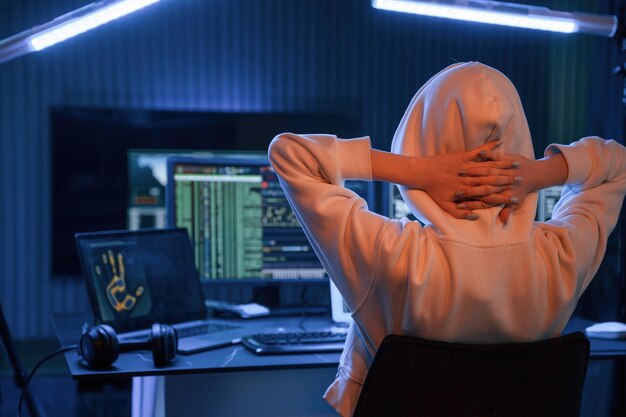 Una joven hacker profesional está en el interior de una computadora con mucha información en las pantallas.