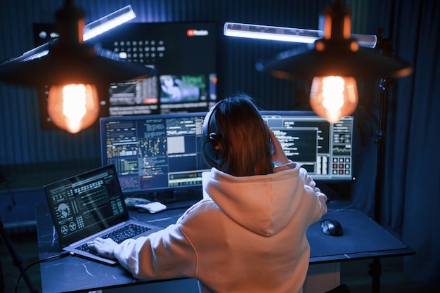 Una joven hacker profesional está en el interior de una computadora con mucha información en las pantallas.