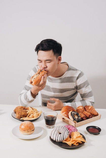 Joven hambriento disfrutando de sandwich en casa