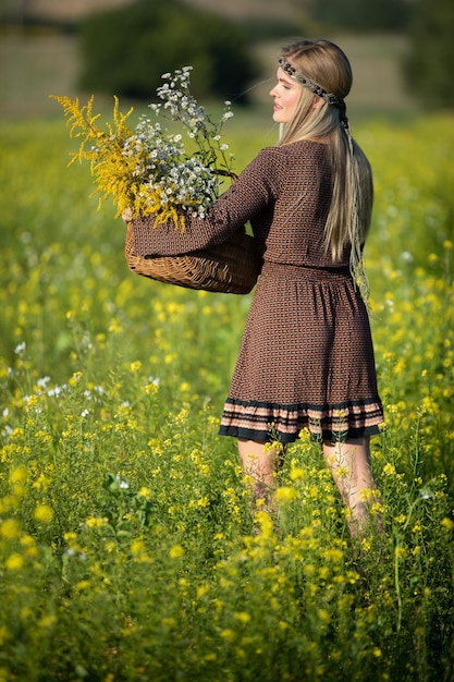 Foto un joven herbalista con una canasta de hierbas camina por un campo lleno de semillas de colza en flor goldenrod y cresto de invierno