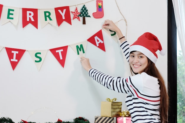 Joven hermosa chica asiática decorar la bandera de adornos de Navidad con felicidad