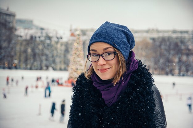 Joven hermosa chica en la calle en invierno en el fondo de decoraciones navideñas