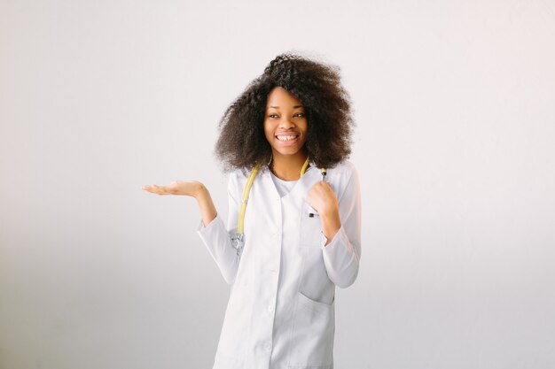 Joven hermosa chica médico en una bata blanca con un estetoscopio. sobre fondo blanco