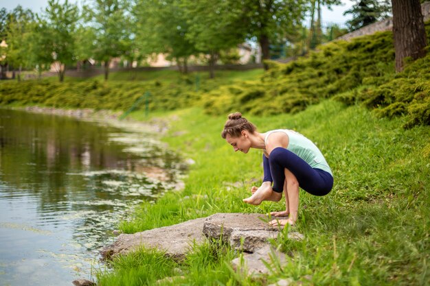 Joven hermosa chica morena caucásica haciendo yoga en un césped verde